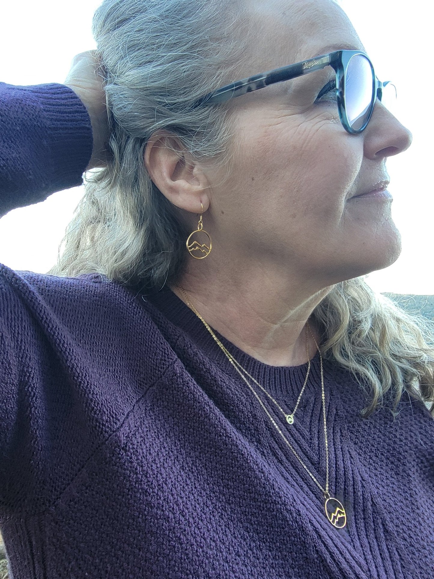 model wearing gold little coastal mountain circle dangle earrings with matching layered gold mountain necklace