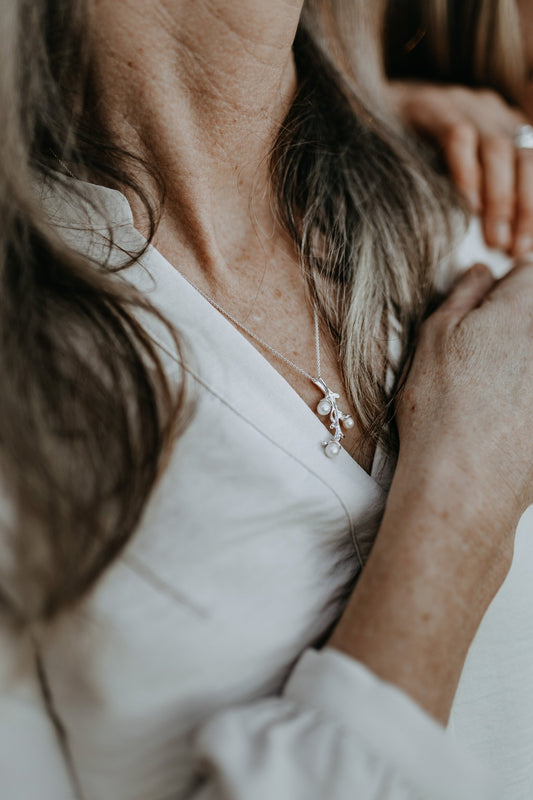 model wearing freshwater pearl necklace with intricate branch design with 3 pearls