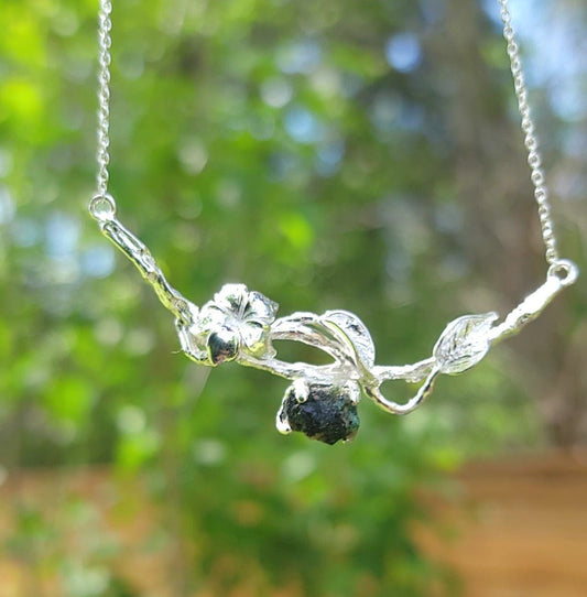 natural raw emerald on silver leaf and flower stick necklace with nature background