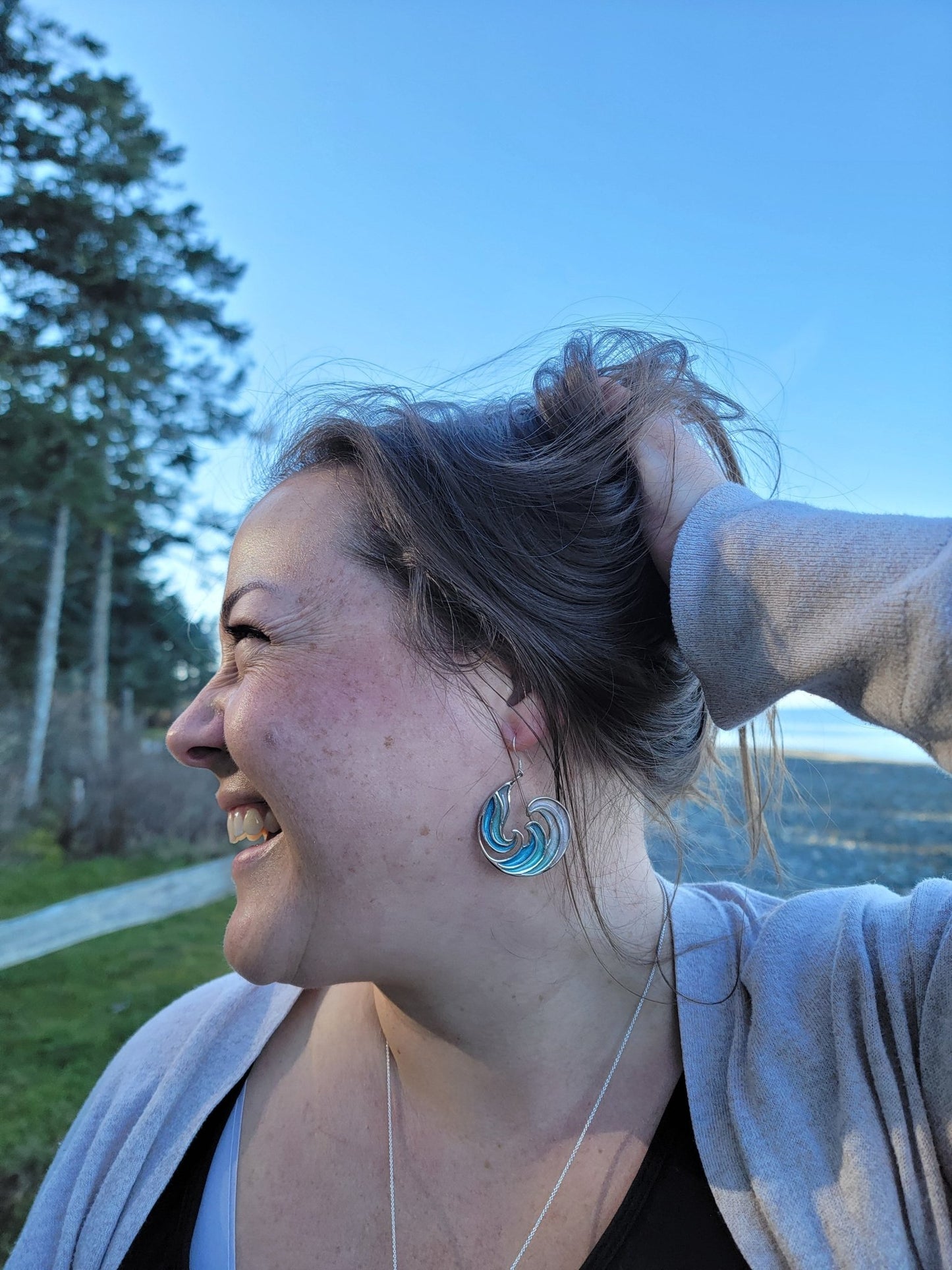 happy model on beach wearing blue Rip Curl Resin and Silver Ocean Surf Wave Earrings