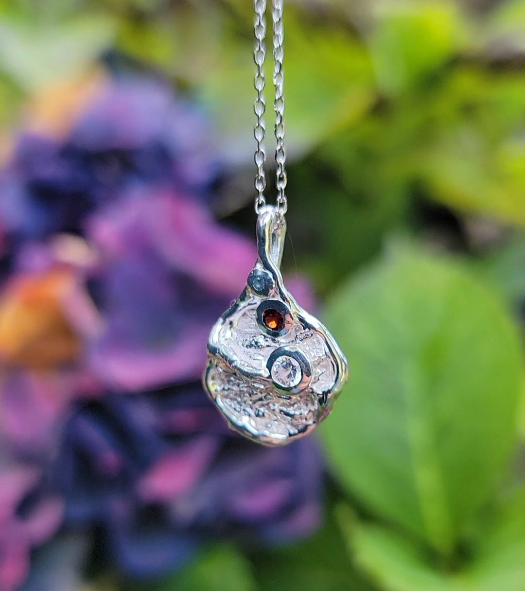one of a kind silver pendant necklace with garnet, zircon and blue topaz gemstones with nature back drop