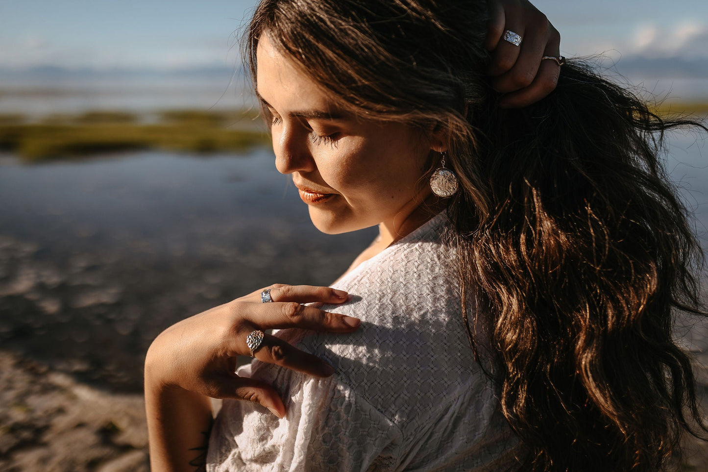 Side view 2 - model wearing silver Talia shell earrings and Meri and Marley silver rings on beach