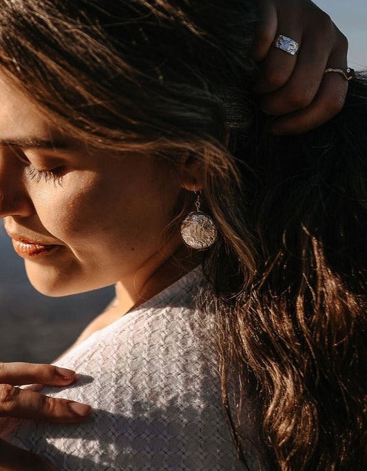 model wearing silver Talia shell earrings and Meri and Marley silver rings on beach