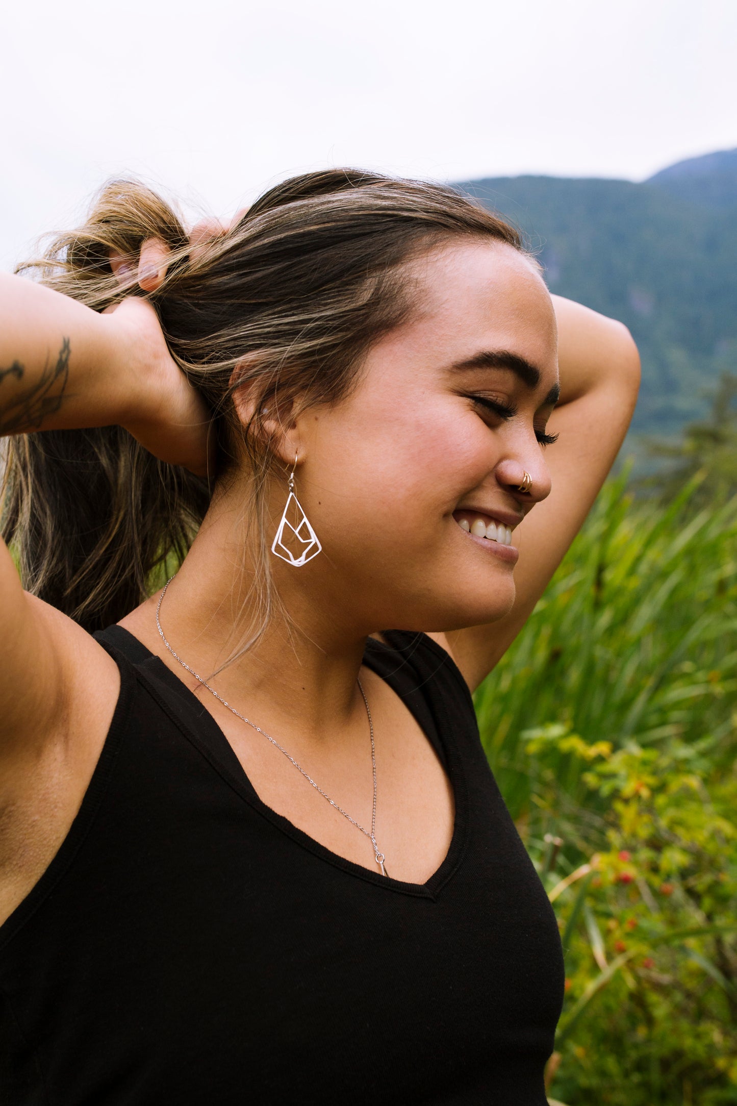 model wearing sterling silver geometric wolf design earring with nature blur background