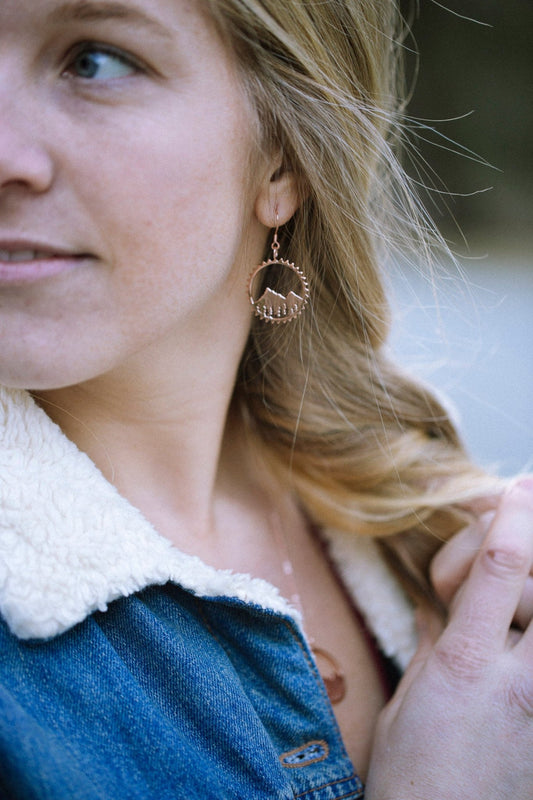 model wearing rose gold Amore bike inspired mountain circle earrings