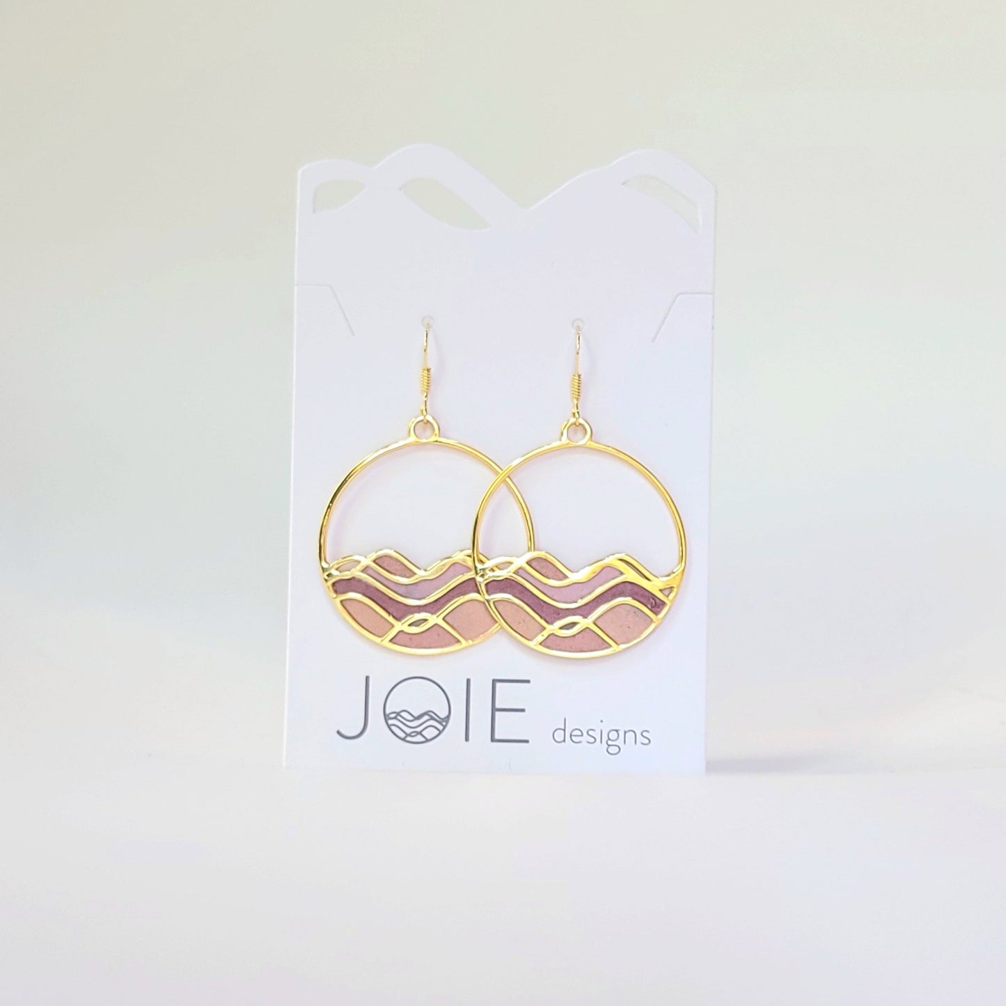 Gold Circle dangle earrings with Golden waves with pink and red resins between the waves creating a stained glass effect