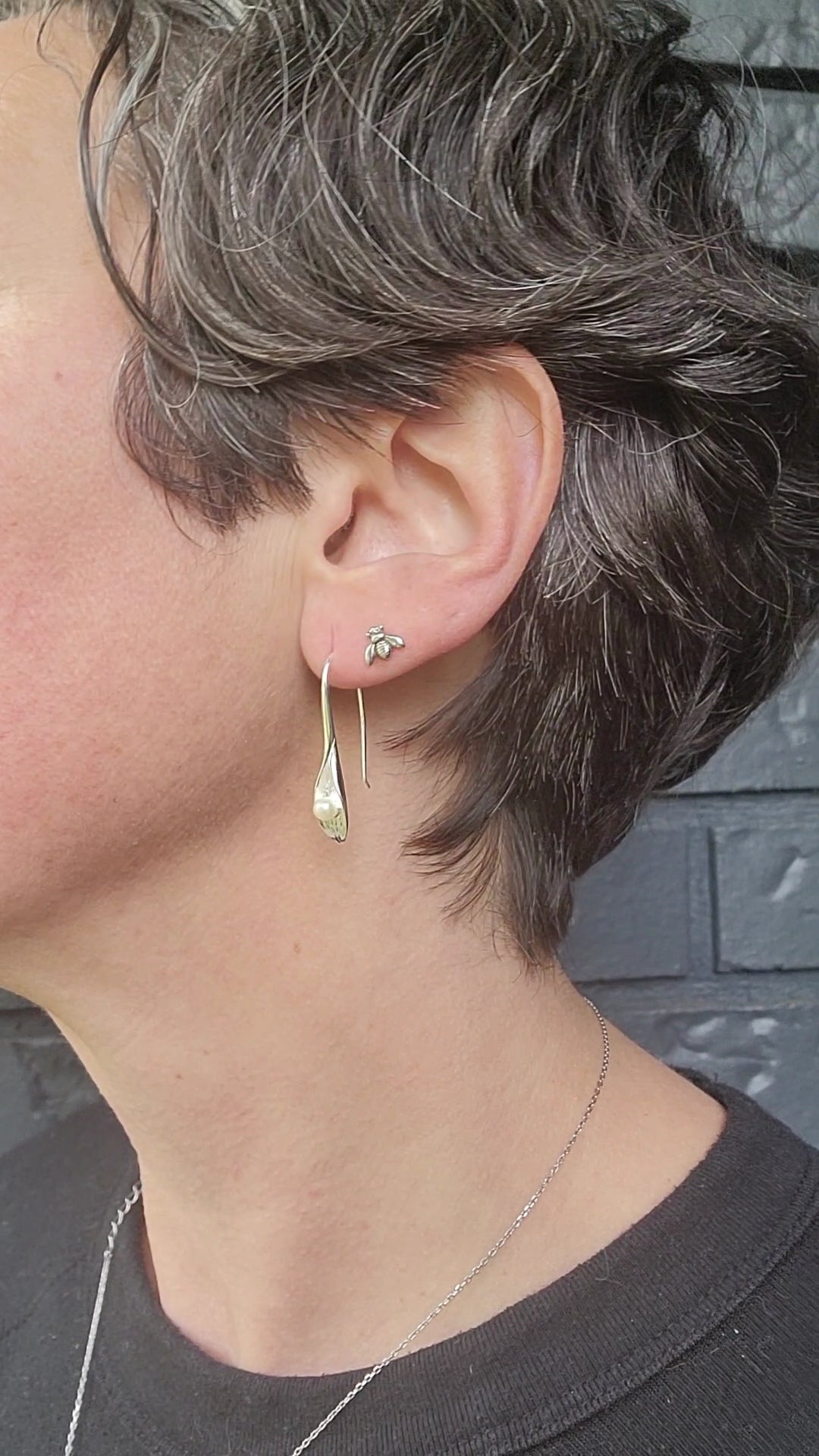 close up of model wearing earring stack of silver Erlea bee stud earring with cala lilly drop earring