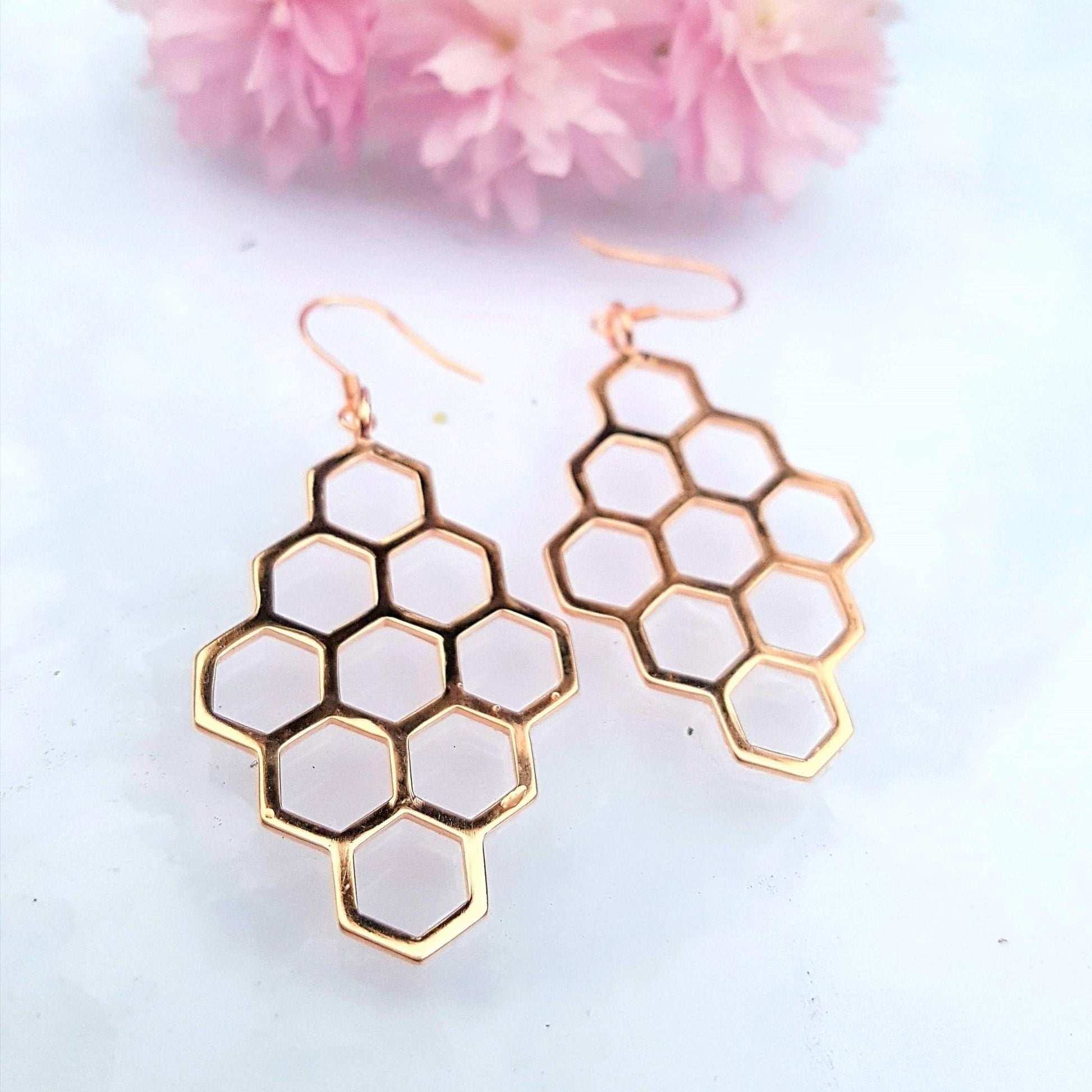 18k plated rose gold diamond shaped honeycomb earrings with light blue background and pink flower