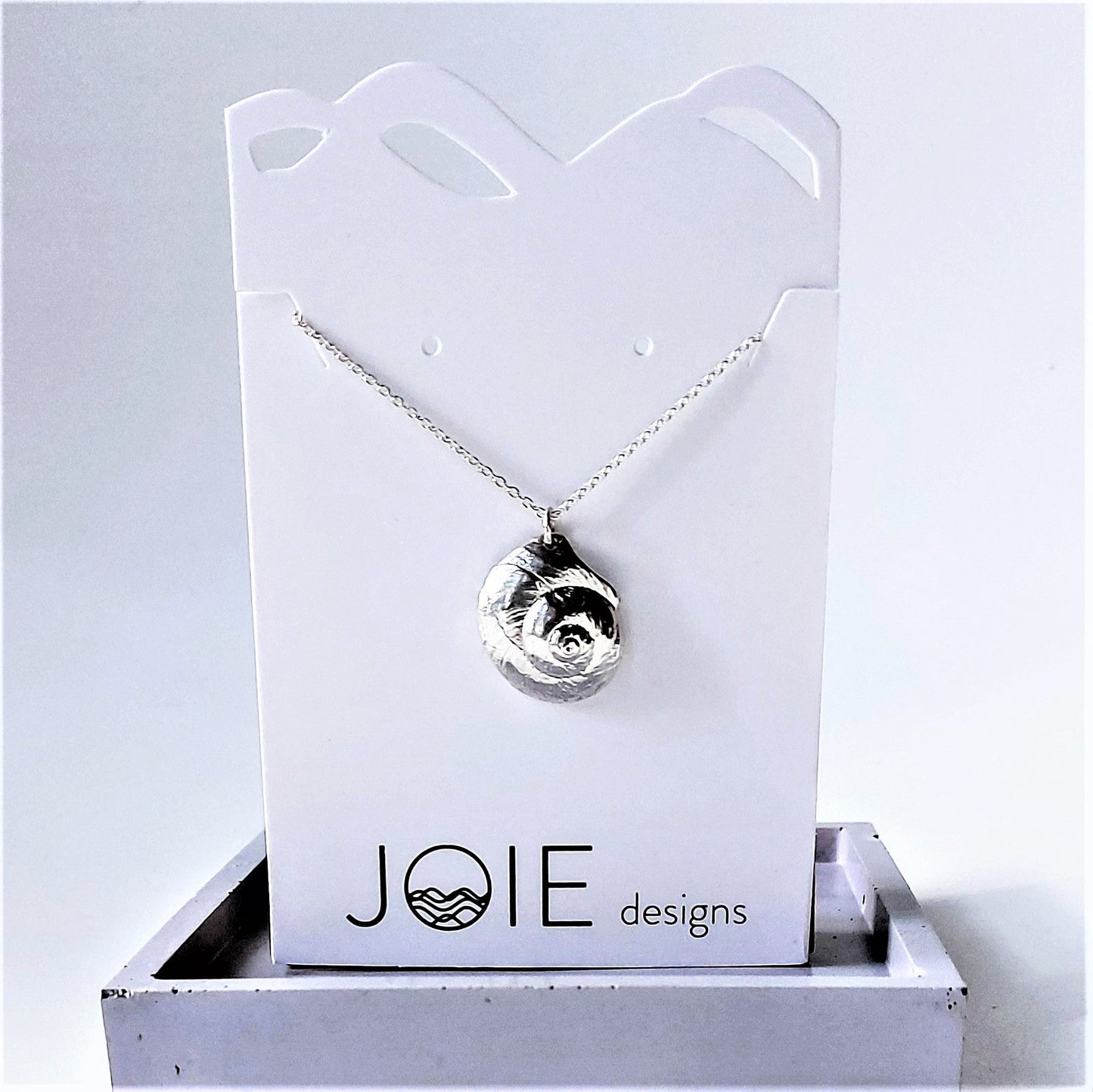 Sterling Silver Luna moon snail seashell necklace on a white jewelry card, ocean jewelry