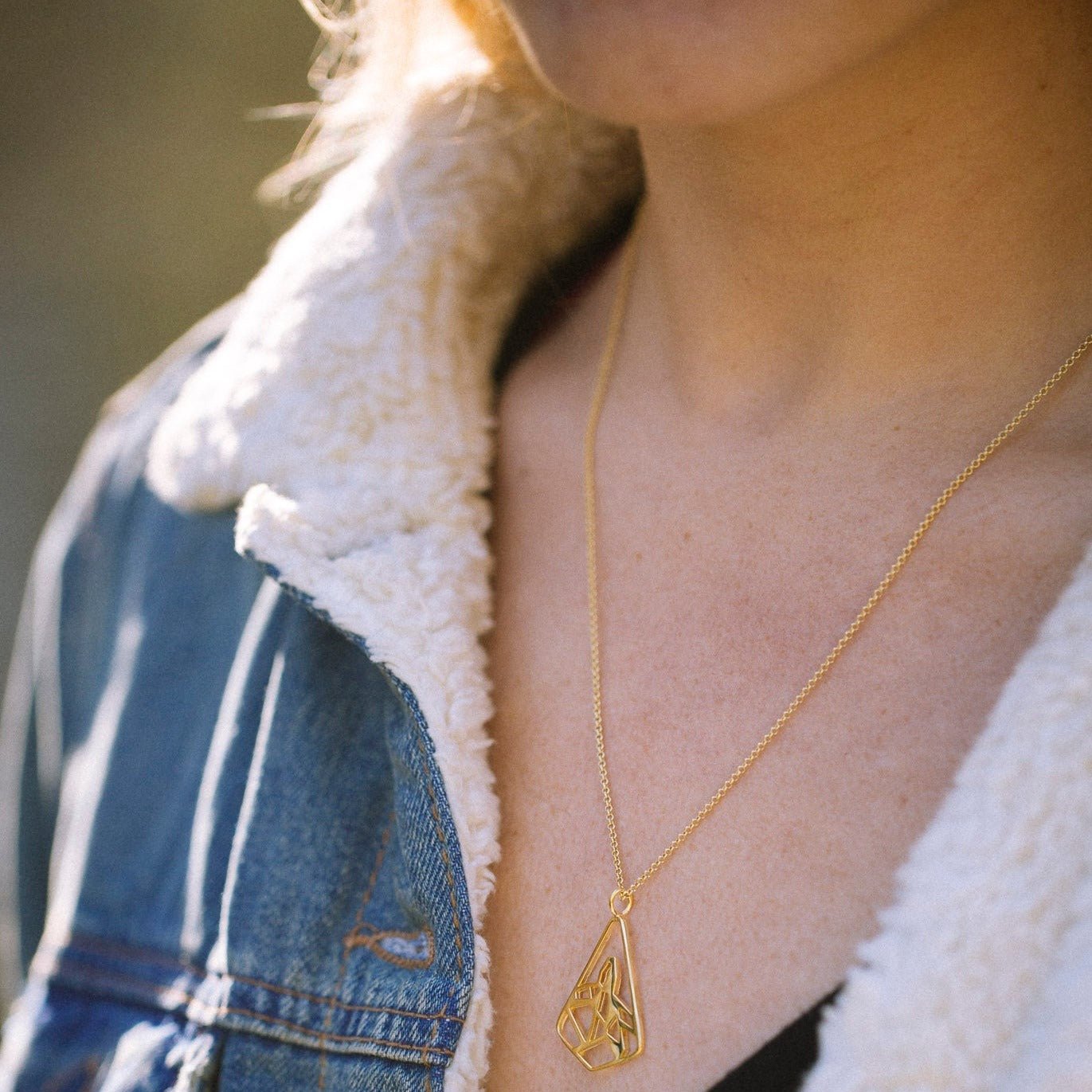 Close up of model wearing gold necklace