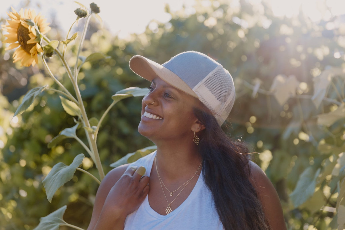 joyful model wearing gold honeycomb necklace layered with mini hexagon gold necklace