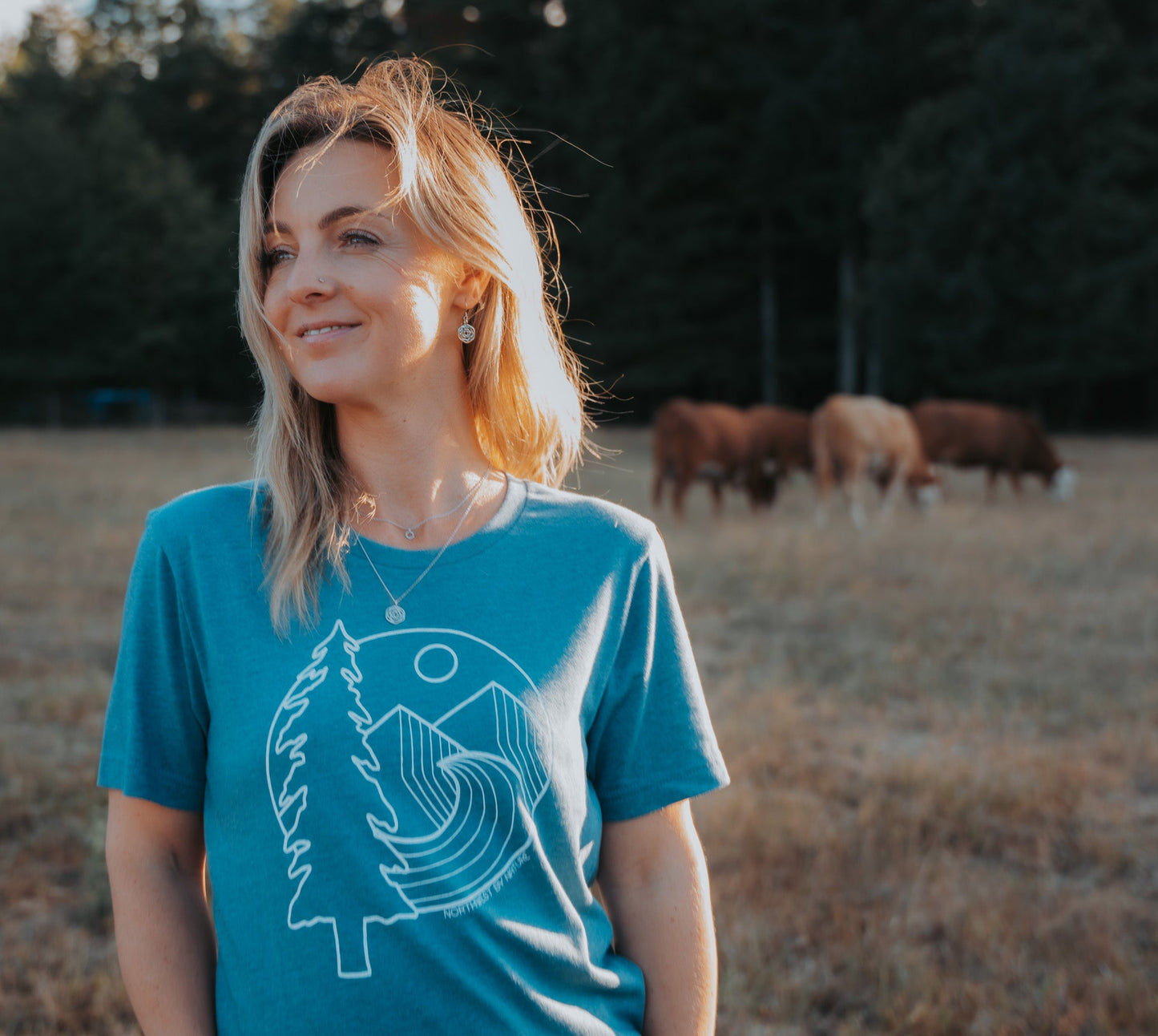model in field wearing layered silver necklaces and silver rose dangle earrings
