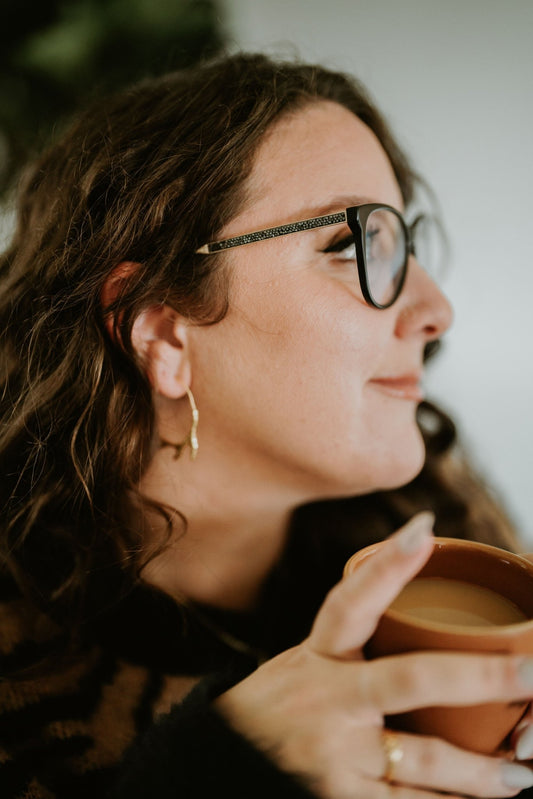 model wearing 18k rose gold plated Sacred Circle Cedar Hoop Earrings with a blur background, nature inspired jewelry