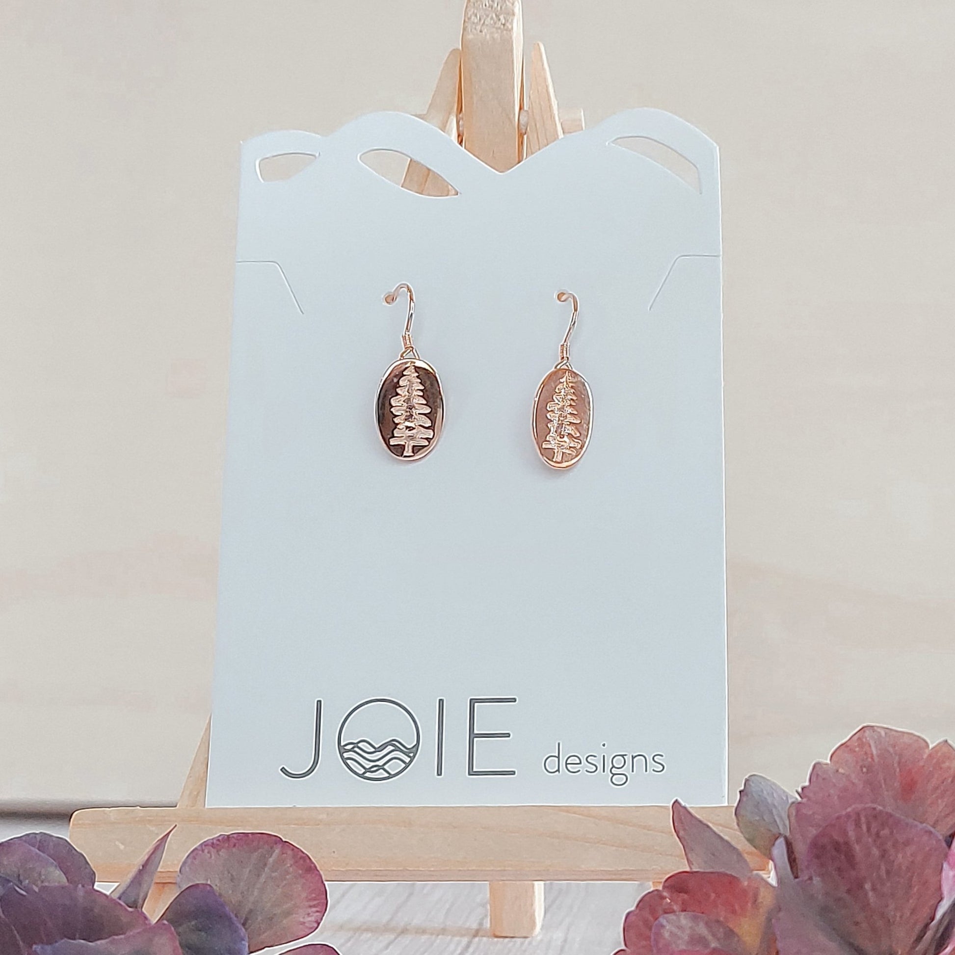 18k rose gold plated Sitka Tree Oval Dangle showcased on a jewelry card