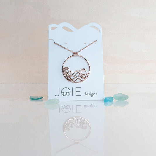 18k plated rose gold round beach wave necklace. surf wave pendant on chain necklace on white jewelry card