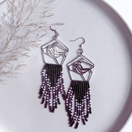 Collaborative art of metal smith and bead artist. Silver bear head with black and white bead fringes
