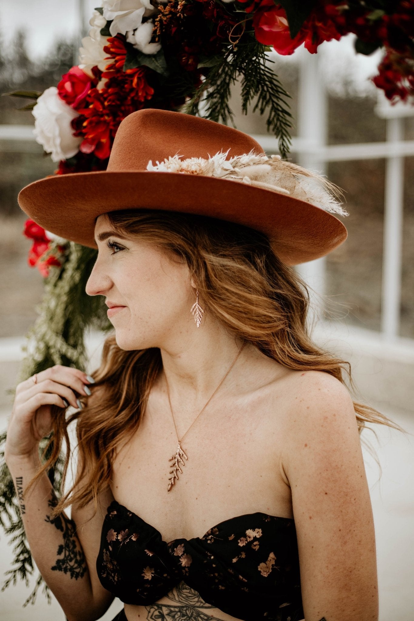 model in hat wearing Nature-inspired cedar leaf necklace in 18k rose gold plating