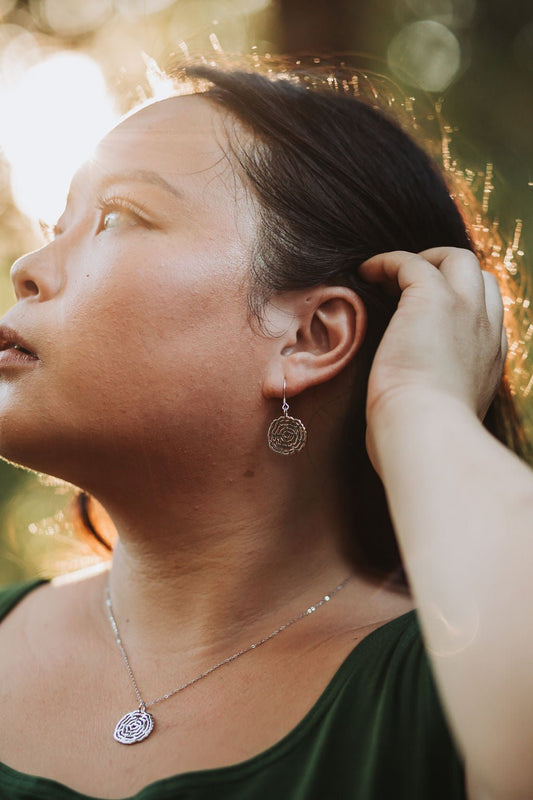 model wearing sterling silver vita tree ring dangle earring with sunny nature background