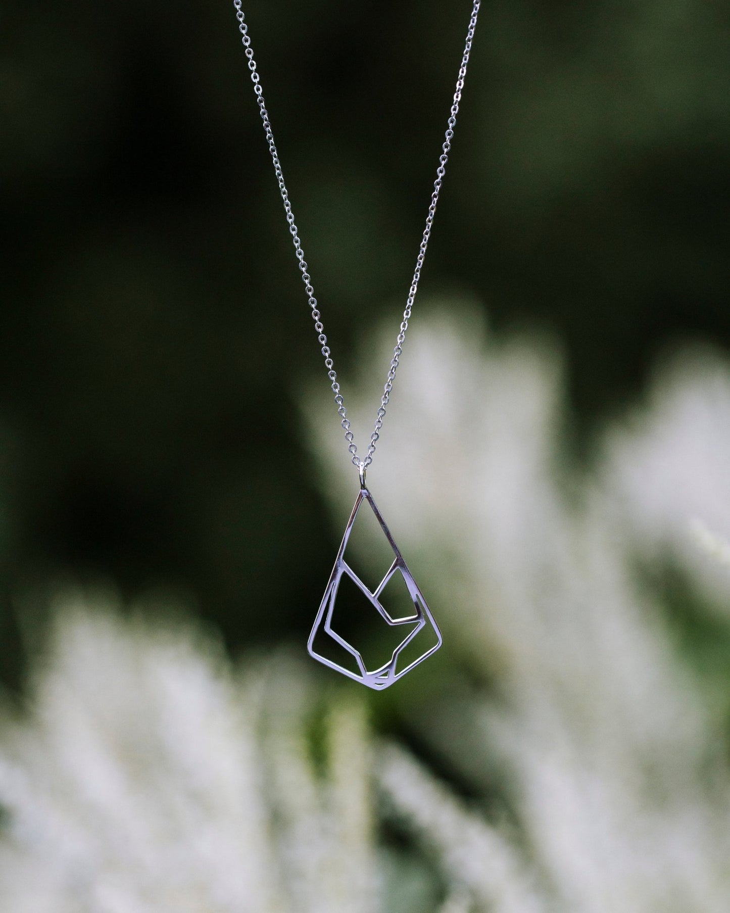 sterling silver wolf pendant necklace displayed with blurred nature background
