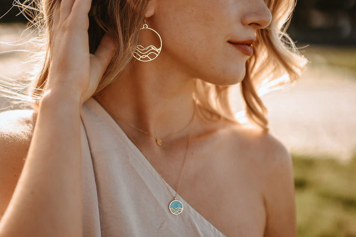 Model wearing nature-inspired minimalist jewelry against beach background