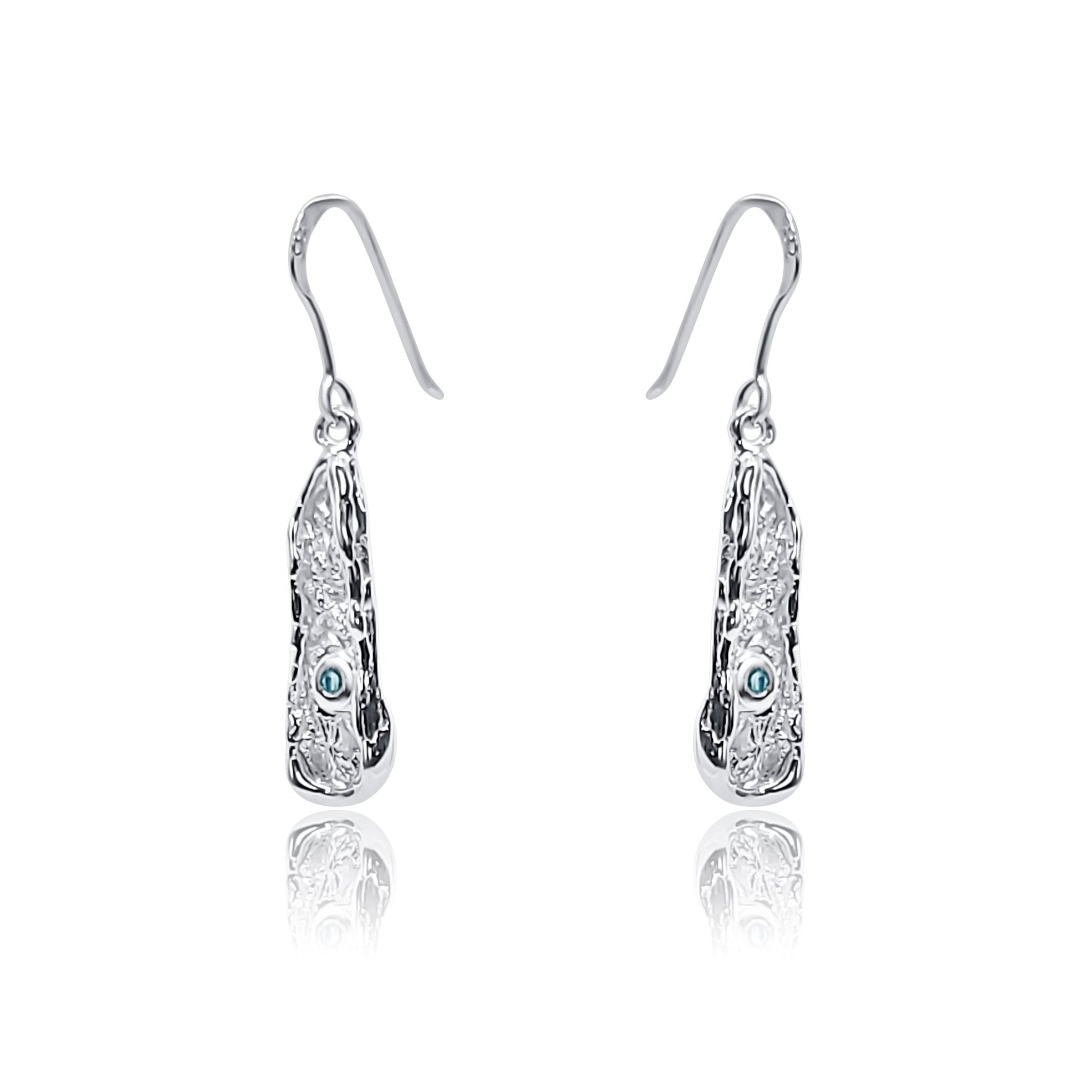 angle view of Blue topaz and organic textured sterling silver dangly earrings. one of a kind handcrafted silver textured earring with natural blue topaz