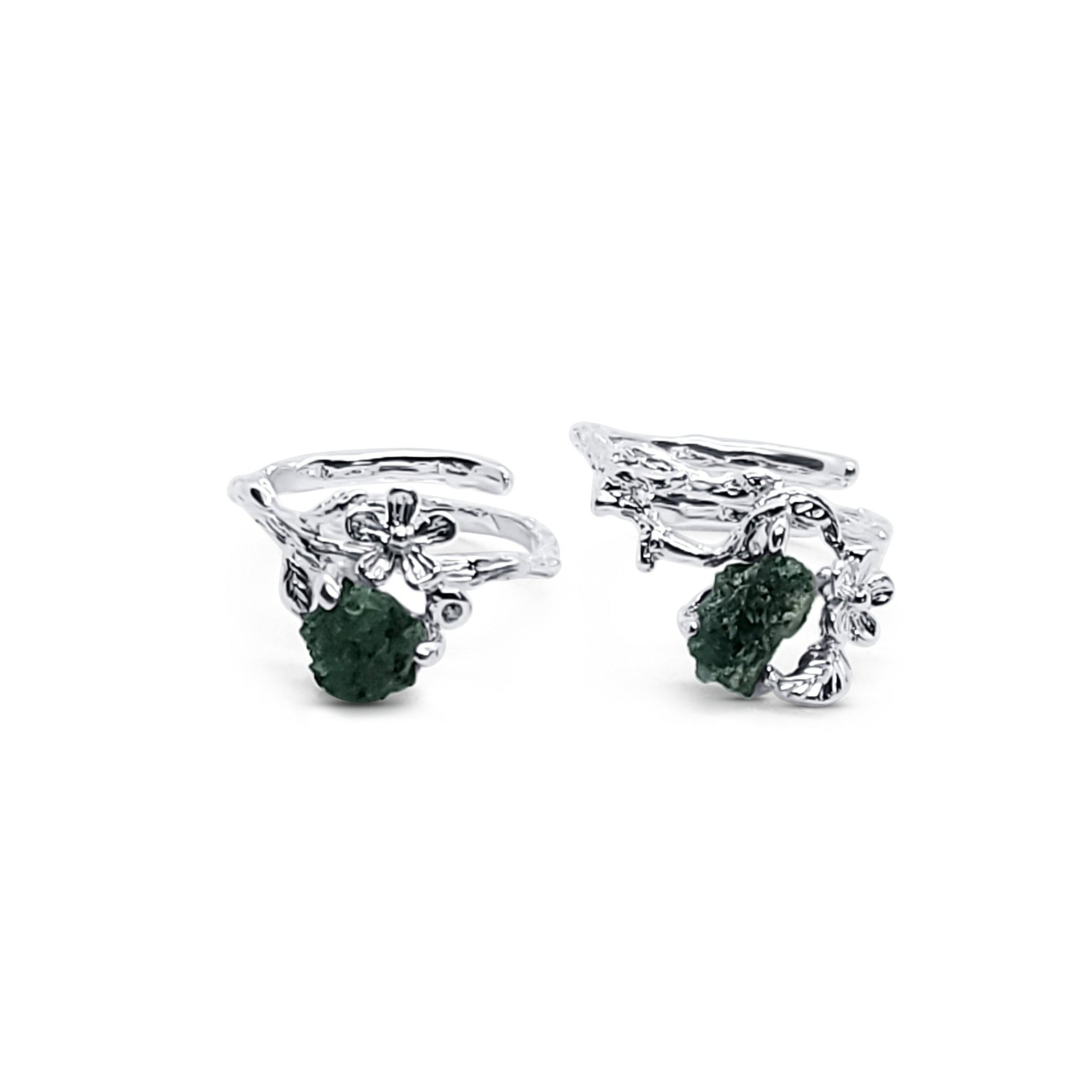 pair of sterling silver flower rings with raw emerald stones in prong settings