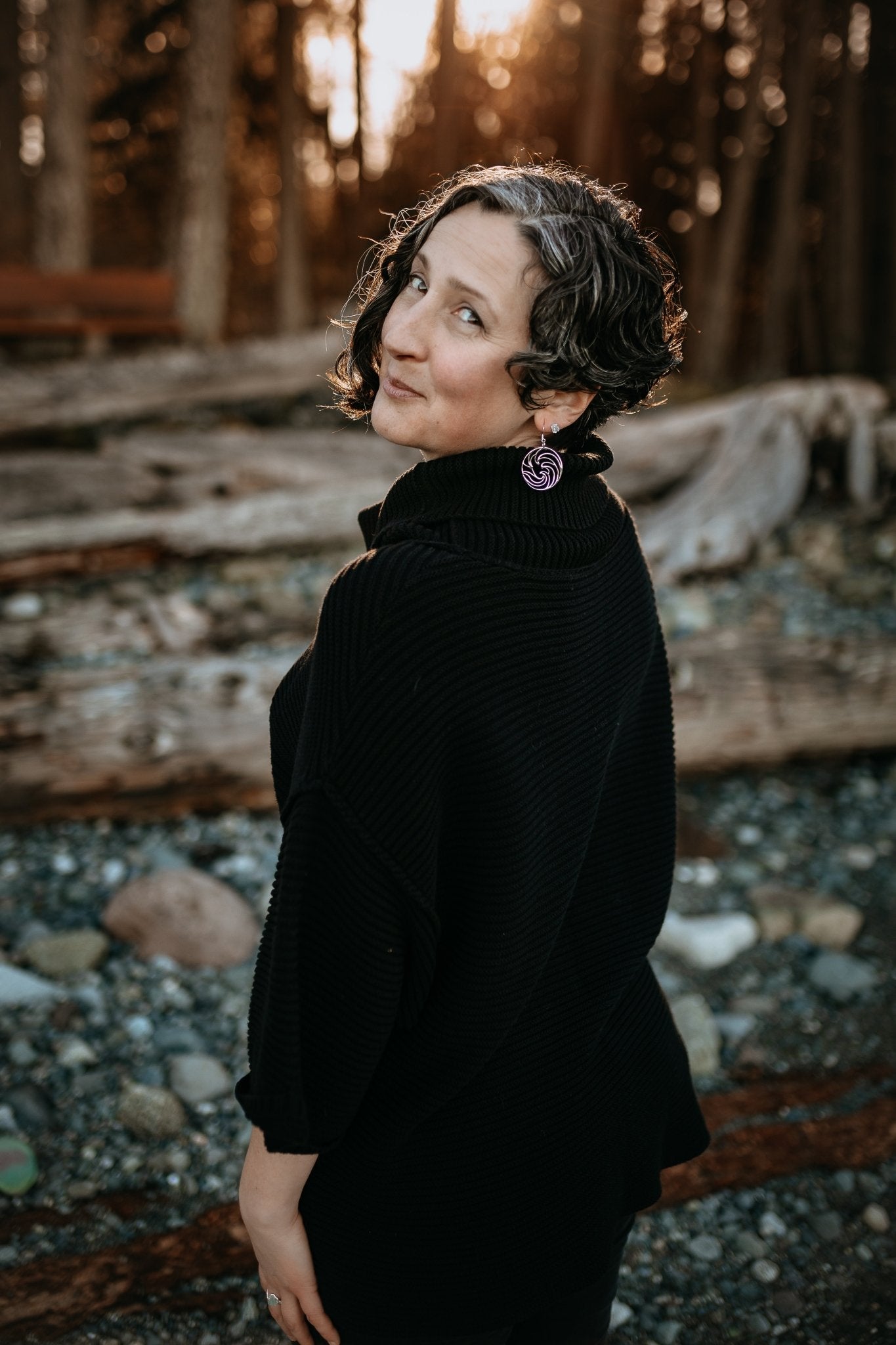model at beach wearing ocean wave silver circle earrings with sun setting in woods