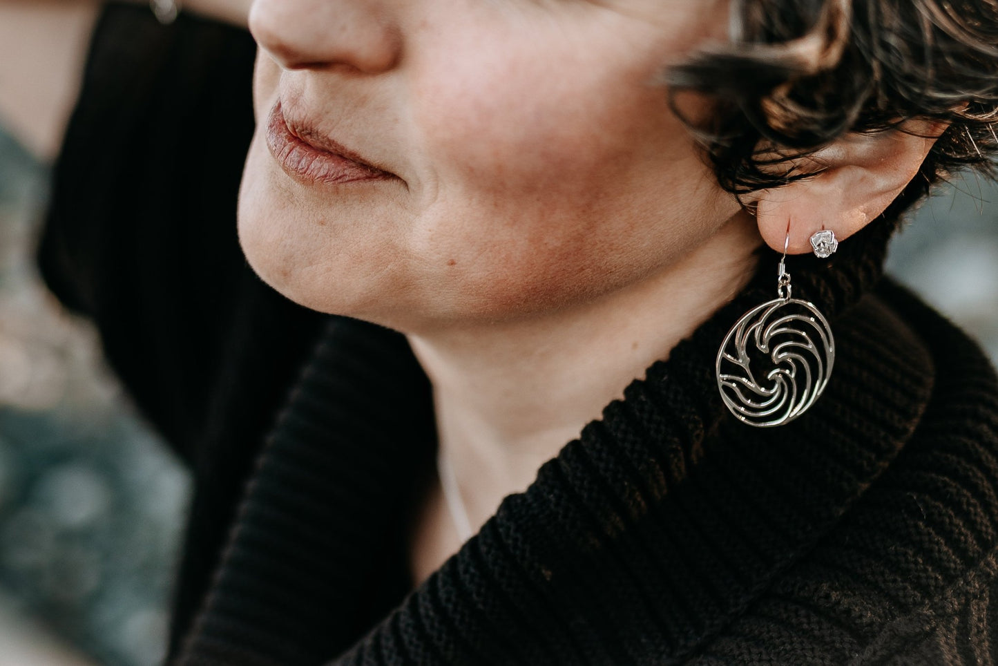close up of model at beach wearing ocean wave silver circle earrings