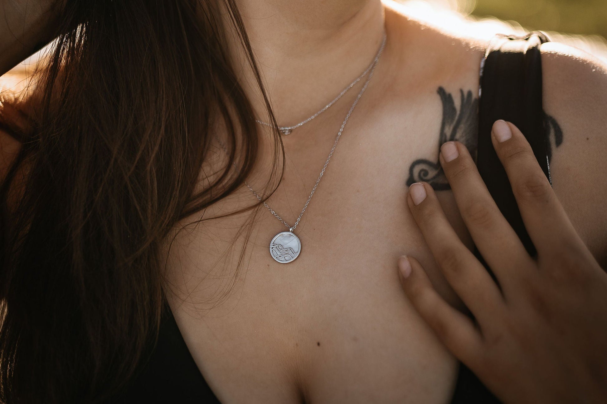 close up of model wearing reversible mother-of-pearl sterling silver circle necklace showing ocean design.