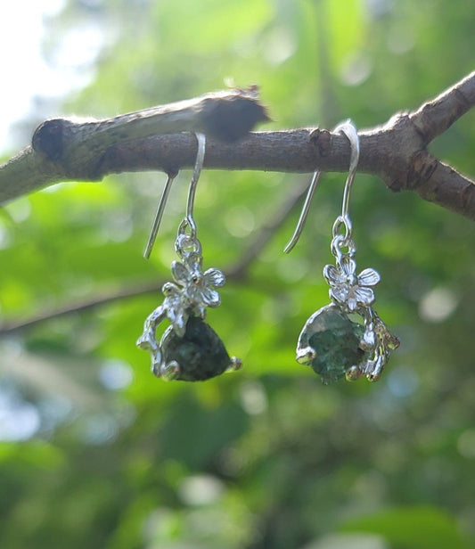 natural raw emerald silver flower earrings hanging from branch outside