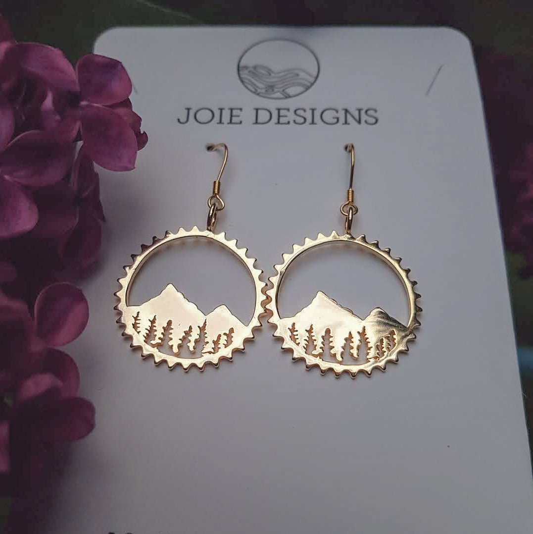 18k gold plated mountainscape and tree earrings shown on jewelry card with purple flowers to the left