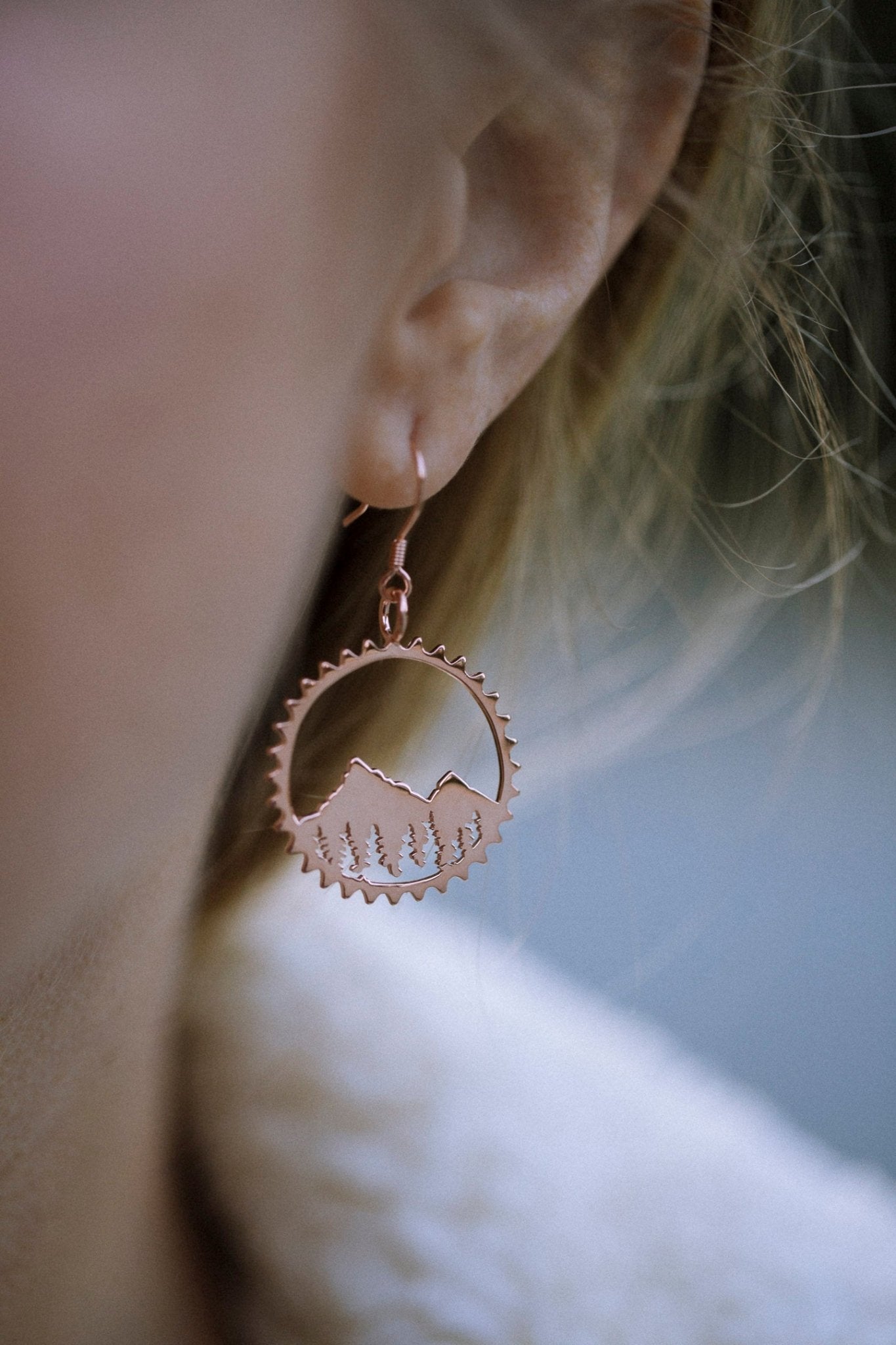 close up of model wearing rose gold Amore bike inspired mountain circle earrings
