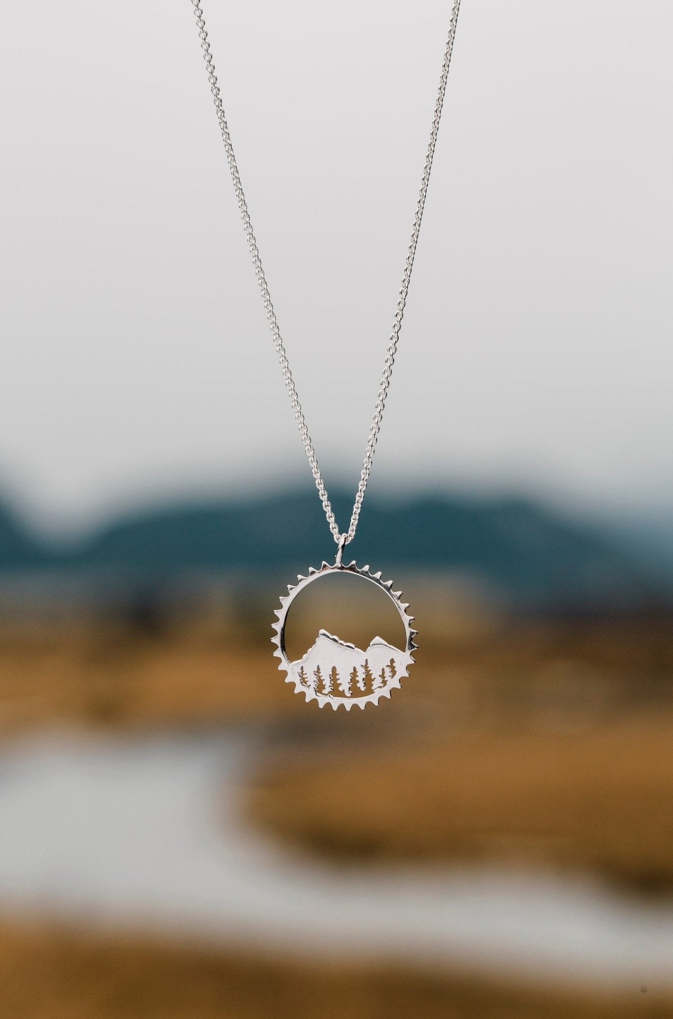 Sterling silver Amore necklace pictured in front of blurred stream and mountain background