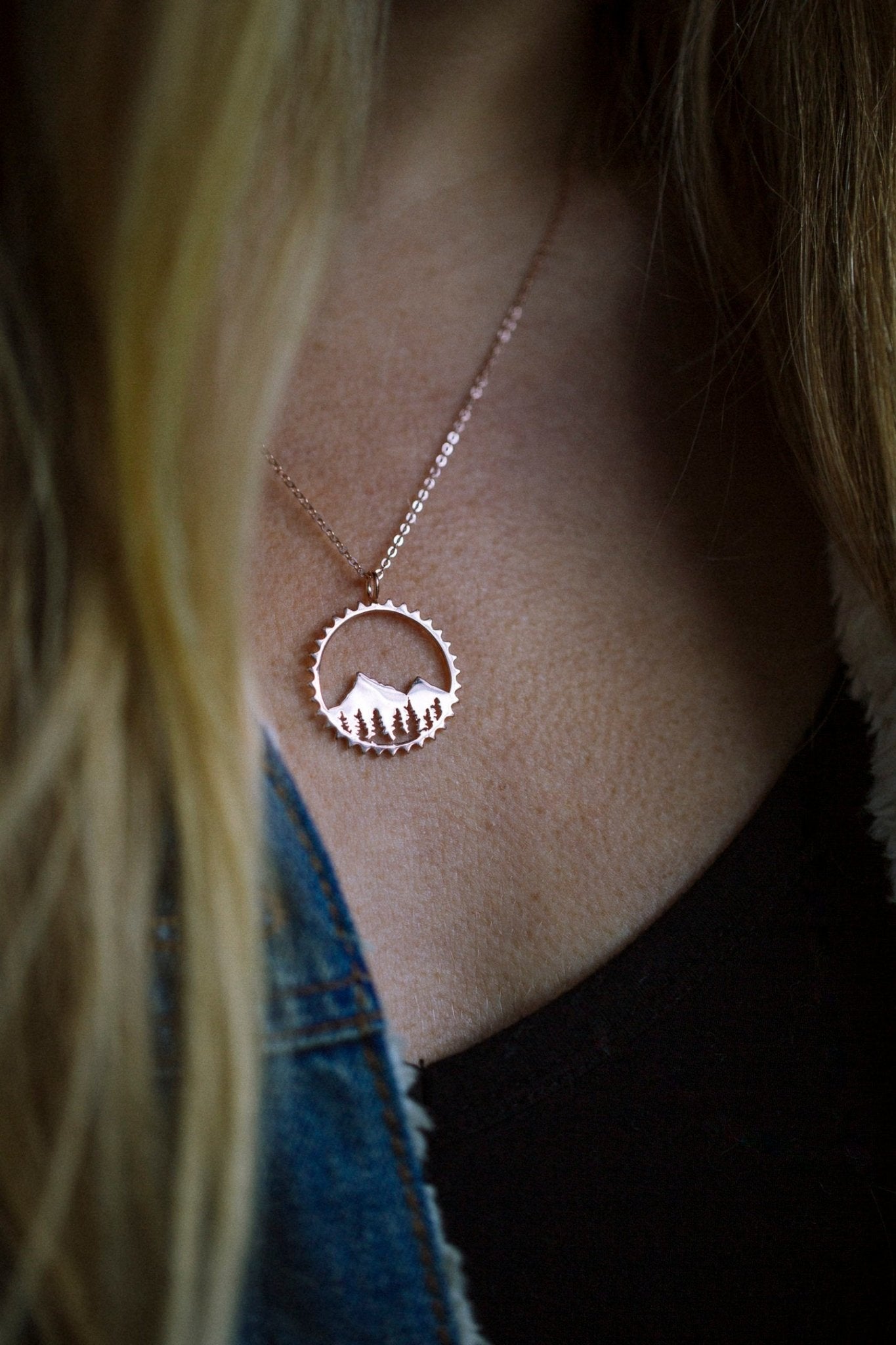 Close up shot of model wearing gold mountain necklace