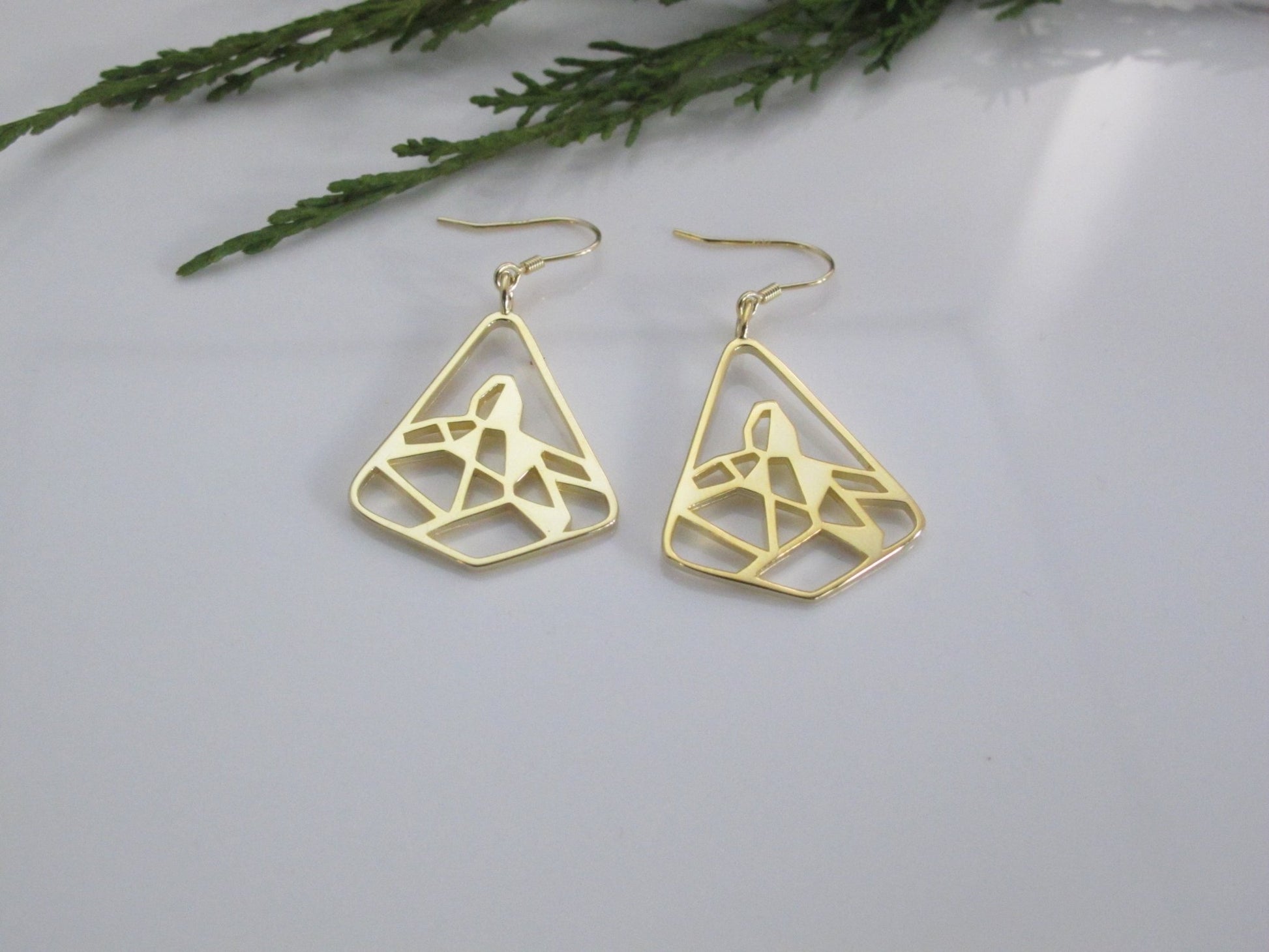 18k yellow gold plated black tusk mountain hook earrings with cedar leaf and white background