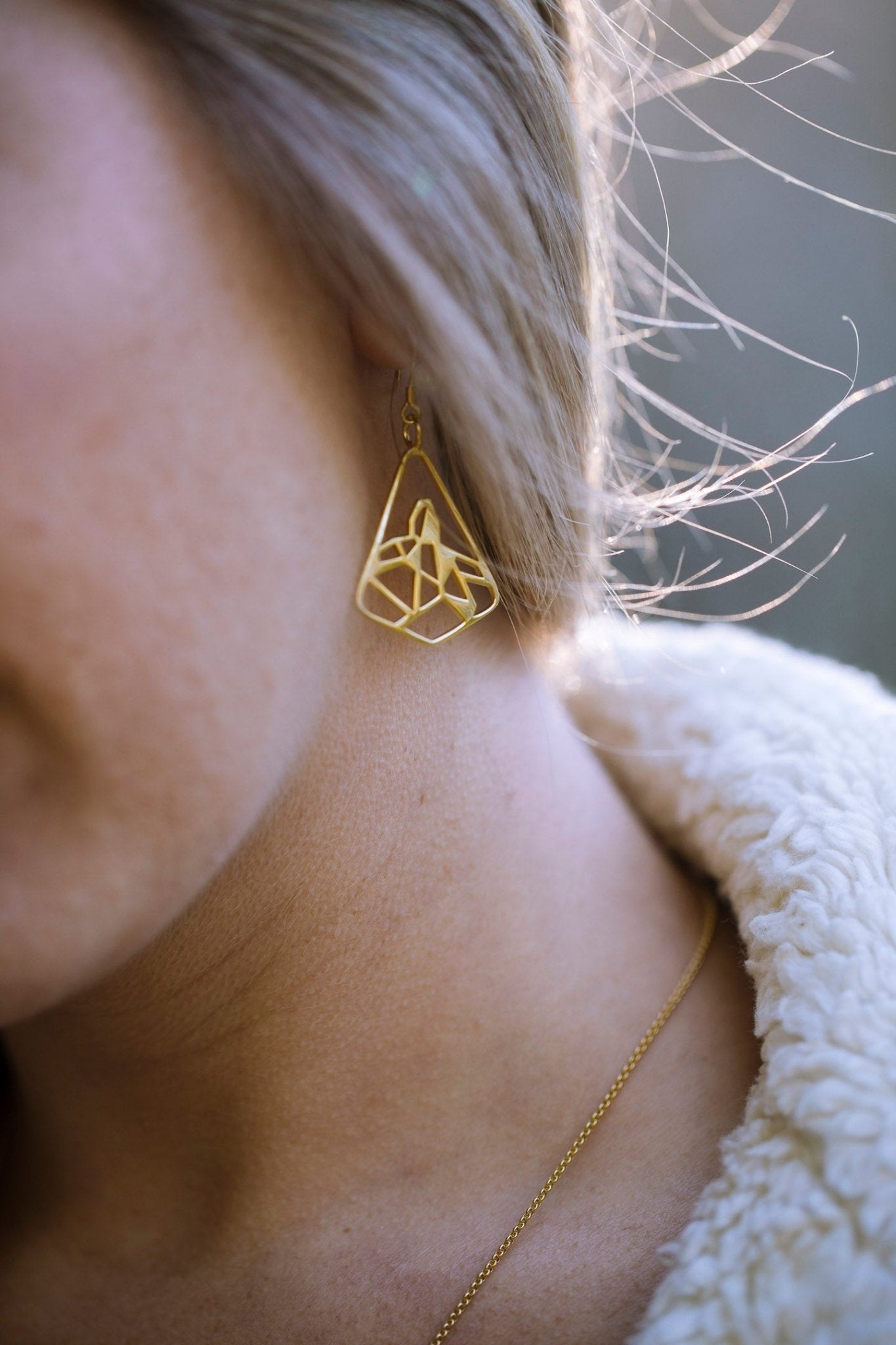 Close up of our black tusk earring in gold. A geometric representation of the icon black tusk peak  inside a diamond shape