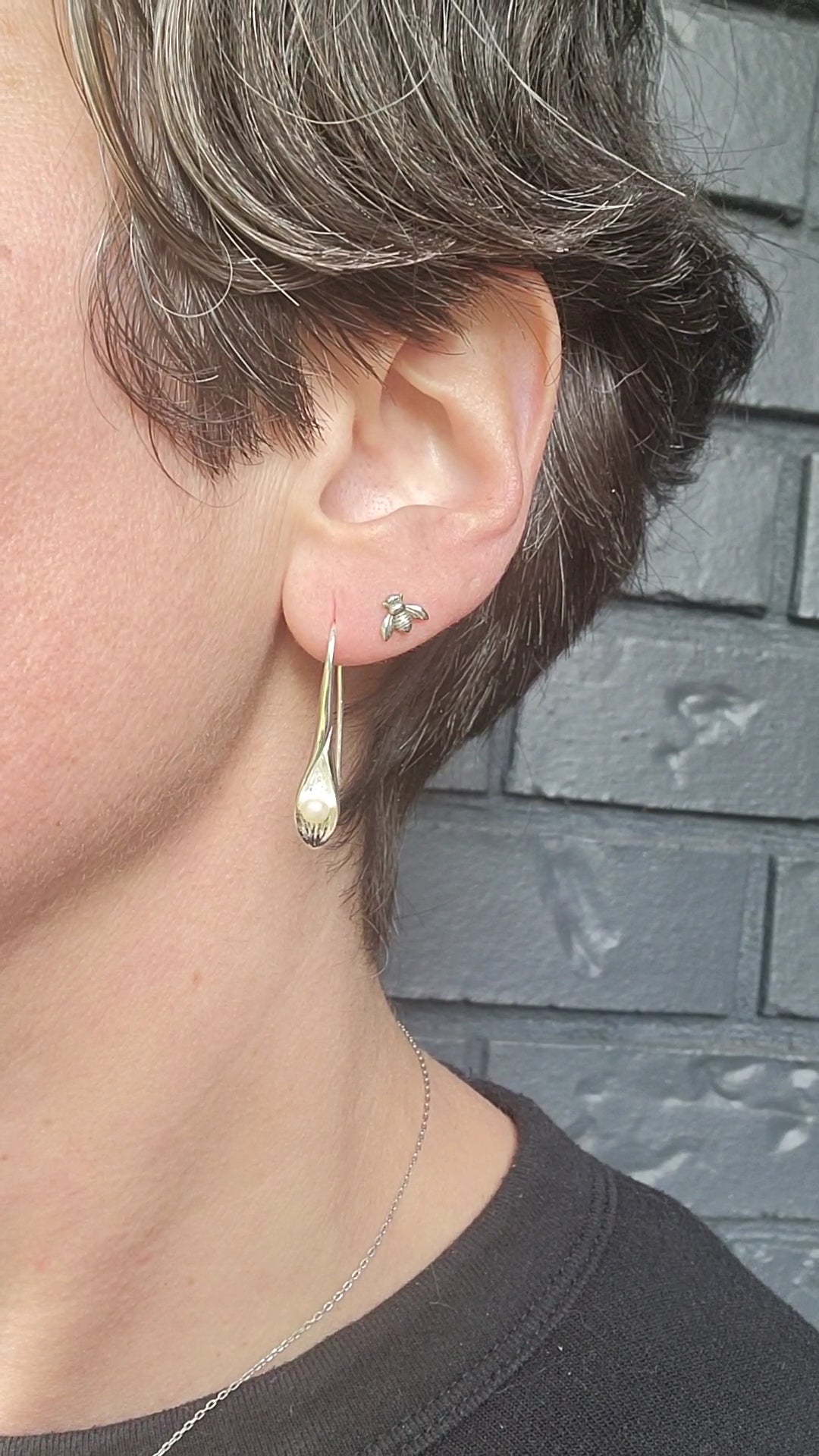 model wearing sterling silver earring stack with cala Lily freshwater pear drop earrings and little bee stud earringr 