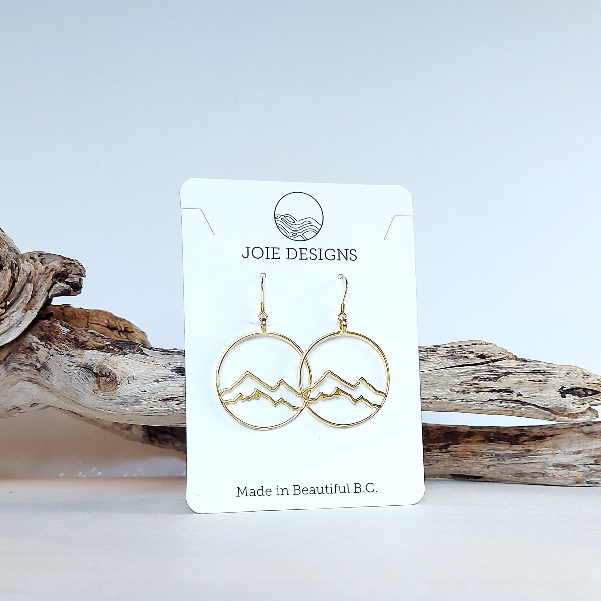 18k yellow gold plated coastal mountain in circle design hook earring shown on a jewelry card with wood and white background