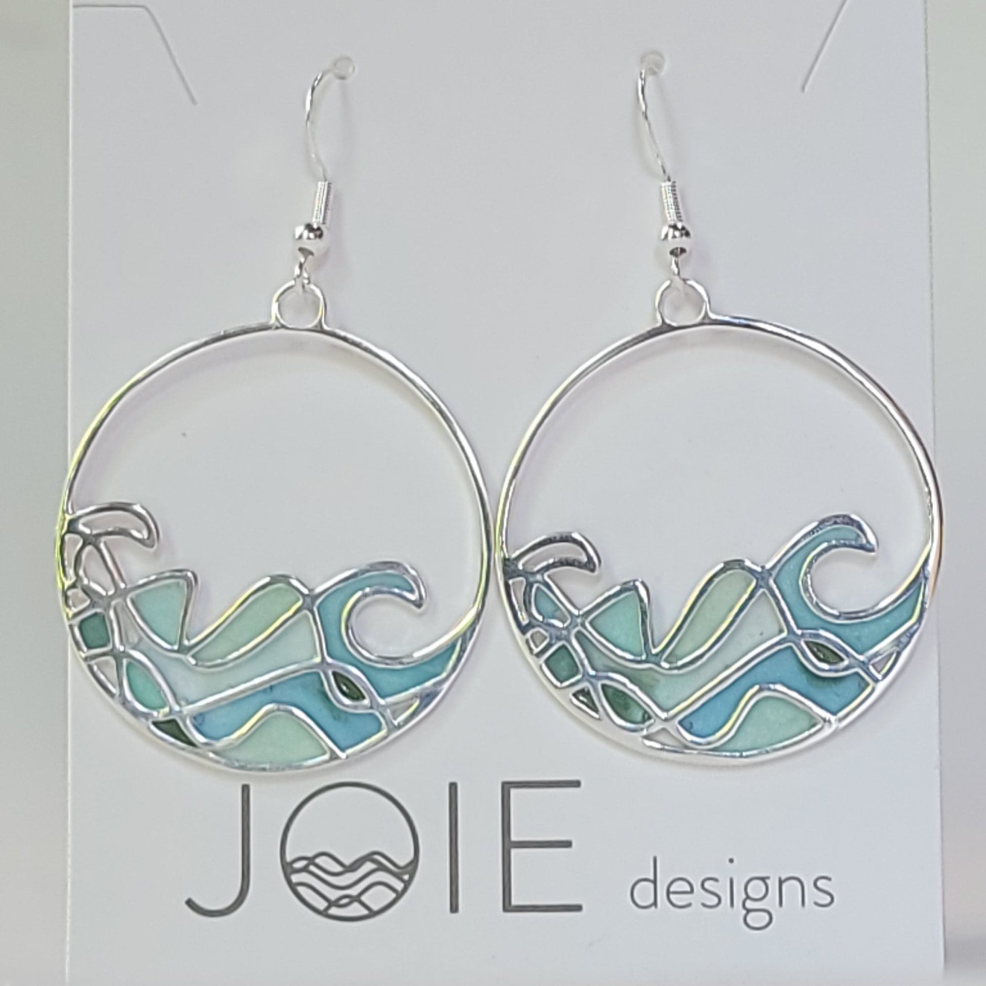 close up of resin and sterling silver ocean wave dangle statement earrings with stained glass effect