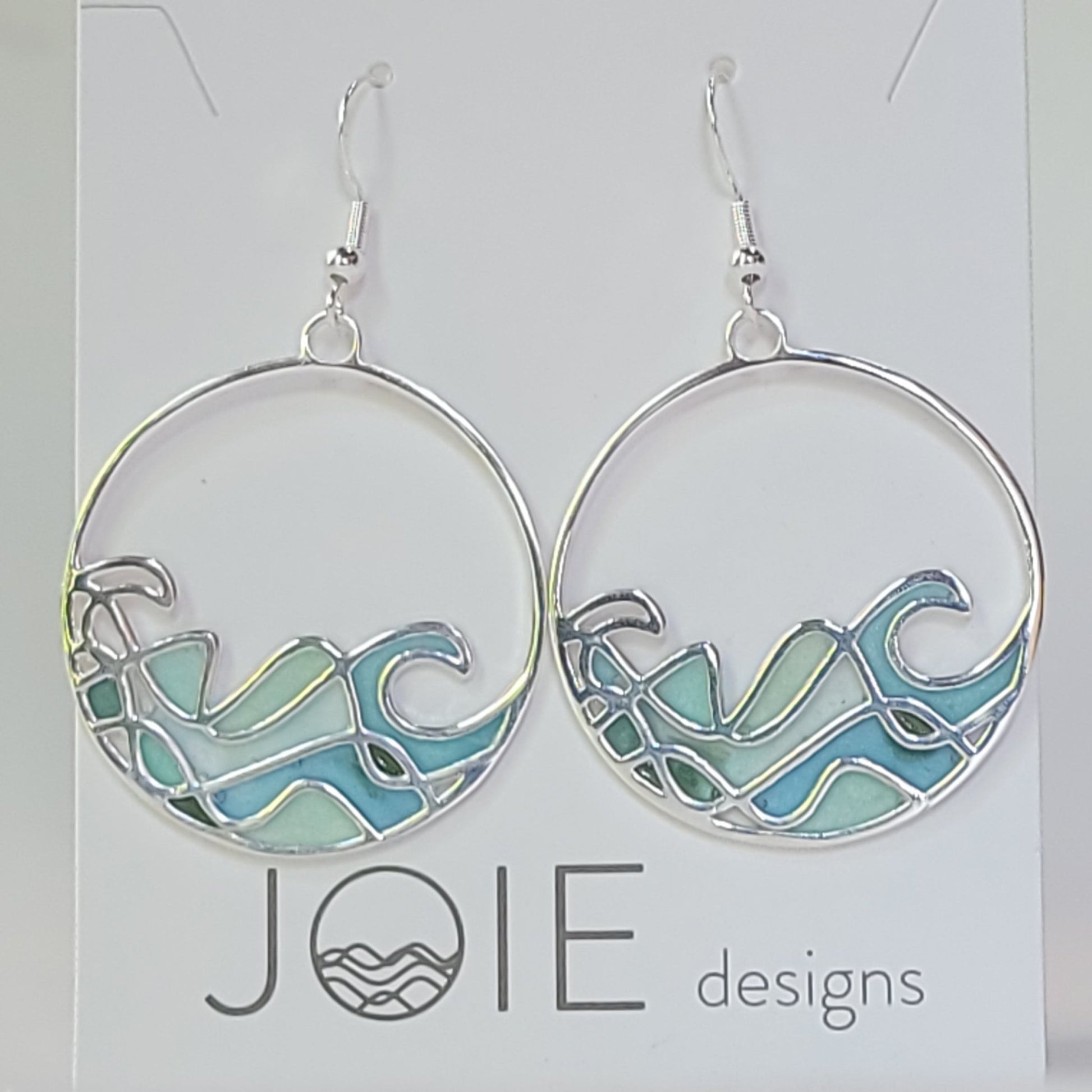 close up of resin and sterling silver ocean wave dangle statement earrings with stained glass effect