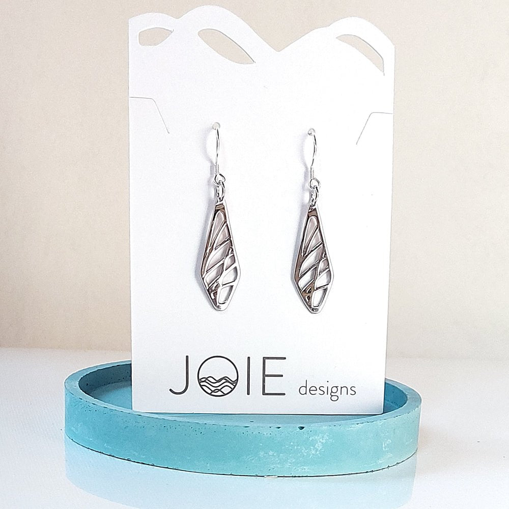 sterling silver diamond-shaped drop earrings with grass pattern on white jewelry card on blue coaster