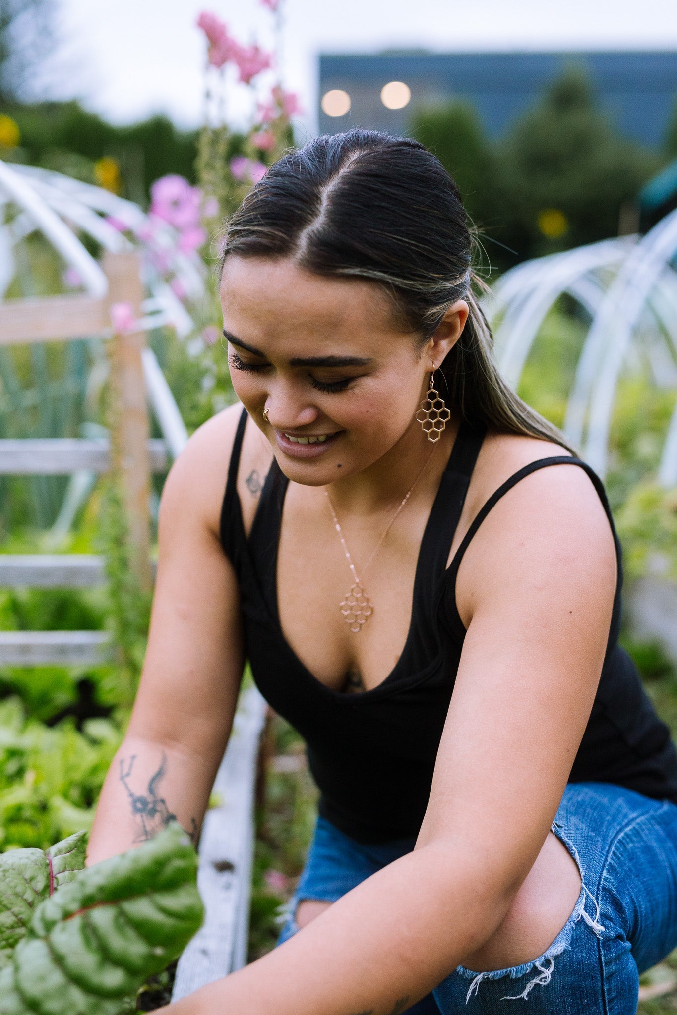 model smiling and wearing sterling silver diamond honey comb dangle earrings in garden