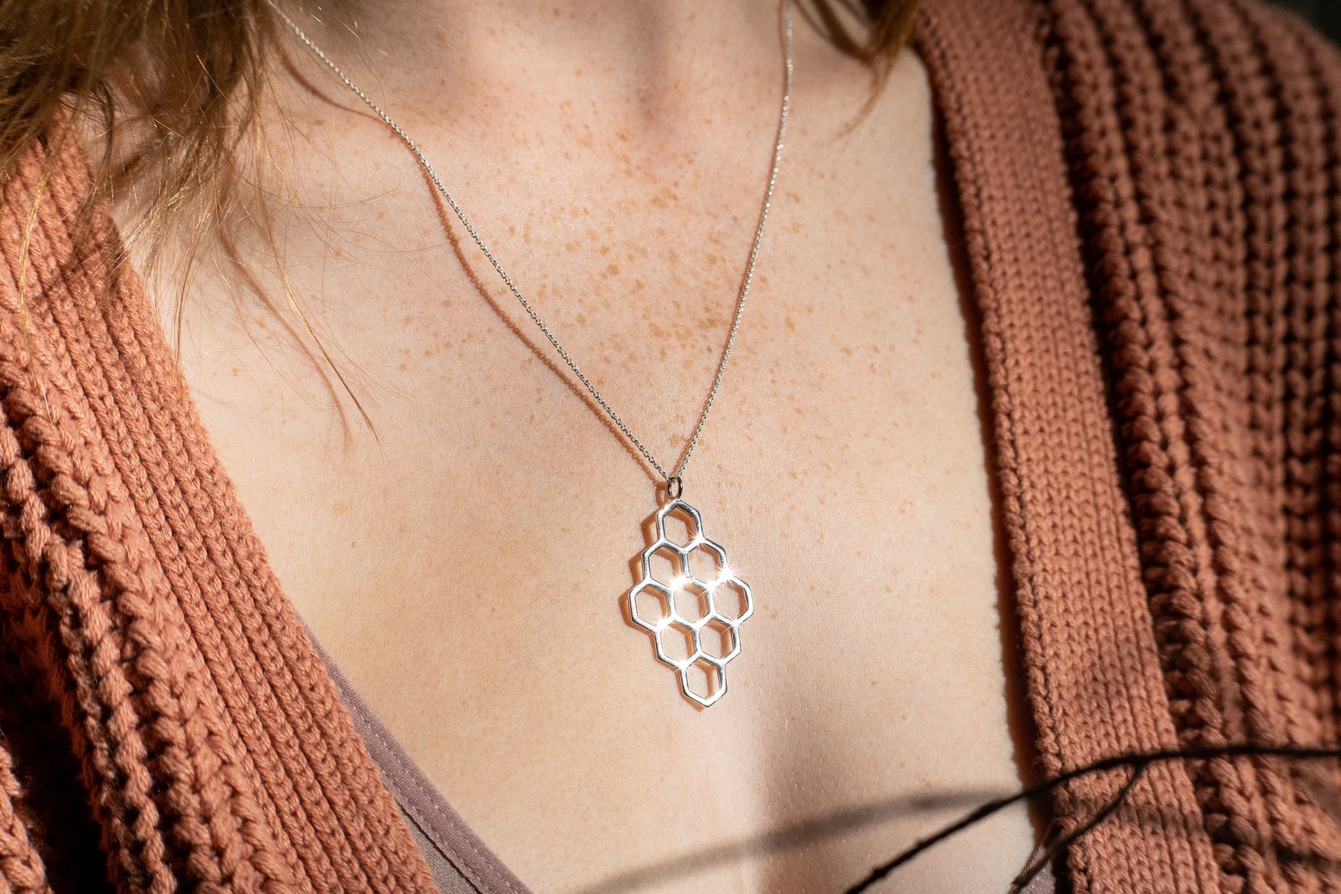 silver dimaond shaped honeycomb pendant necklace glimmering in the sun