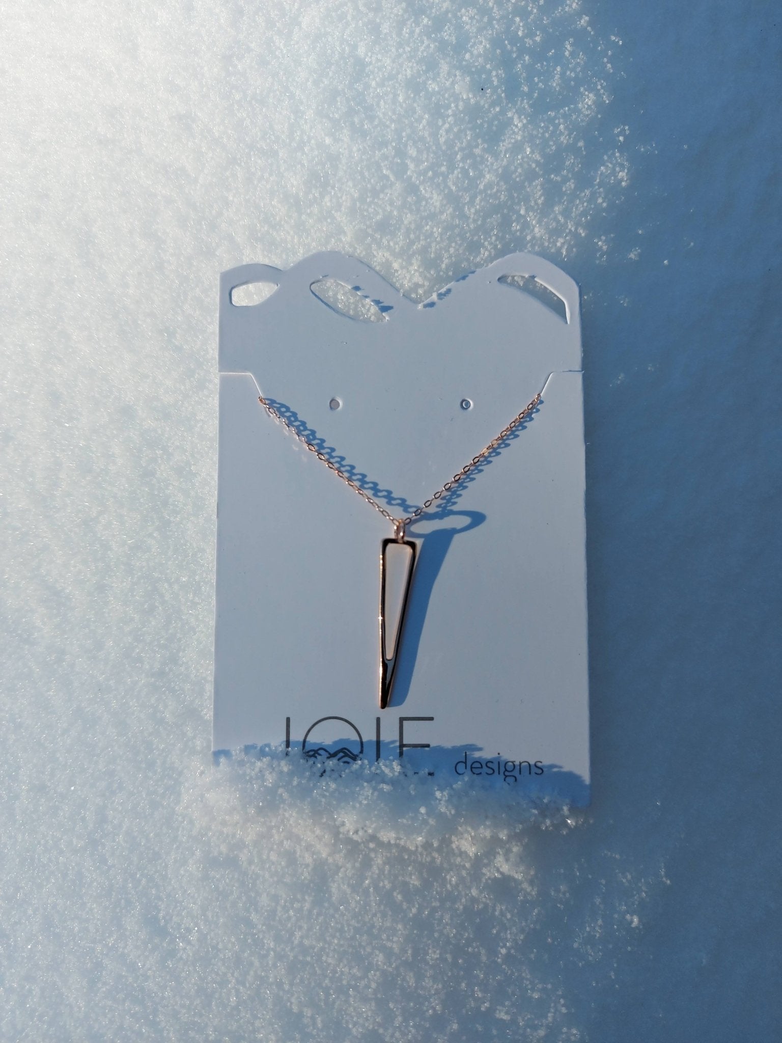 18k rose gold plated icicle design pendant necklace showcased on a jewellery card with fresh snow background
