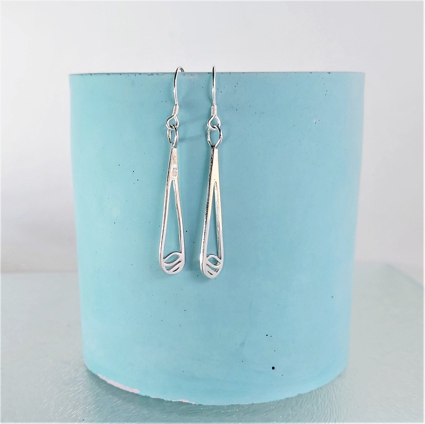 925 sterling silver Indra raindrop design earrings hanging on turquoise blue concrete vase