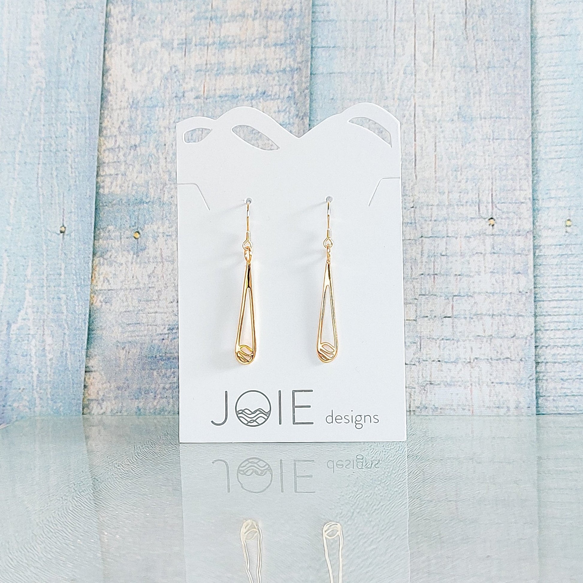 18k yellow gold plated indra raindrop design earrings showcased on a jewellery card with blue wooden background