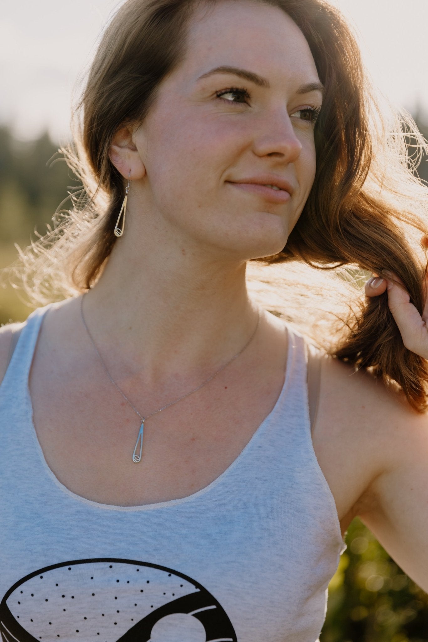 model wearing Indra sterling silver  rain and water drop earrings and water drop necklace outside in nature with sun shining