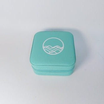 Turquoise zippered jewelry travel case with High Tide Joie Logo on lid
