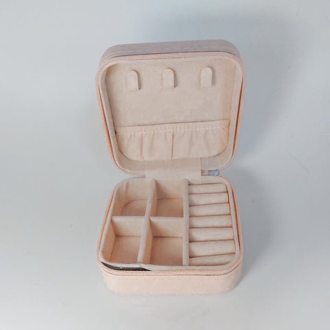 pink travel jewellery case opened showing 4 compartments, 3 necklace hangers, pouch and 6 ring holders in faux suede