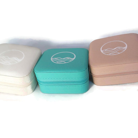 Vegan leather square travel cases for jewelry shown in 3 colors: beige, turquoise, and pink